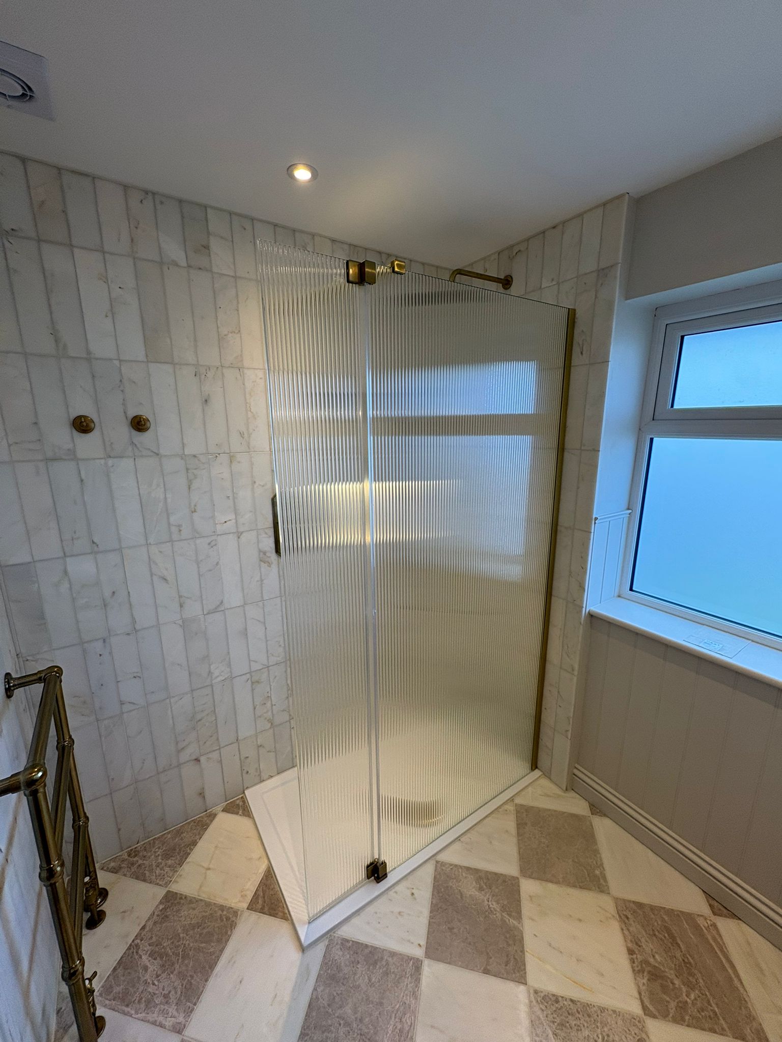 Marble walk-in shower with fluted glass and chequerboard floor